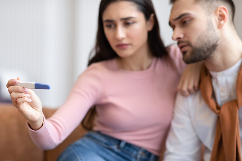 A woman and man read an at-home pregnancy test.