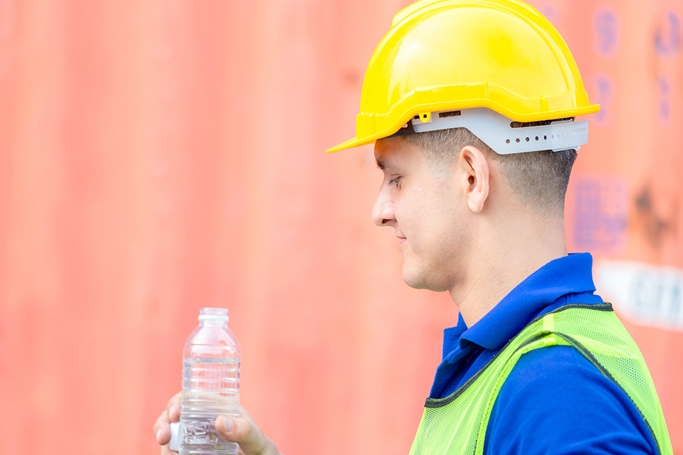 Close up of construction worker in hard hat drinking water